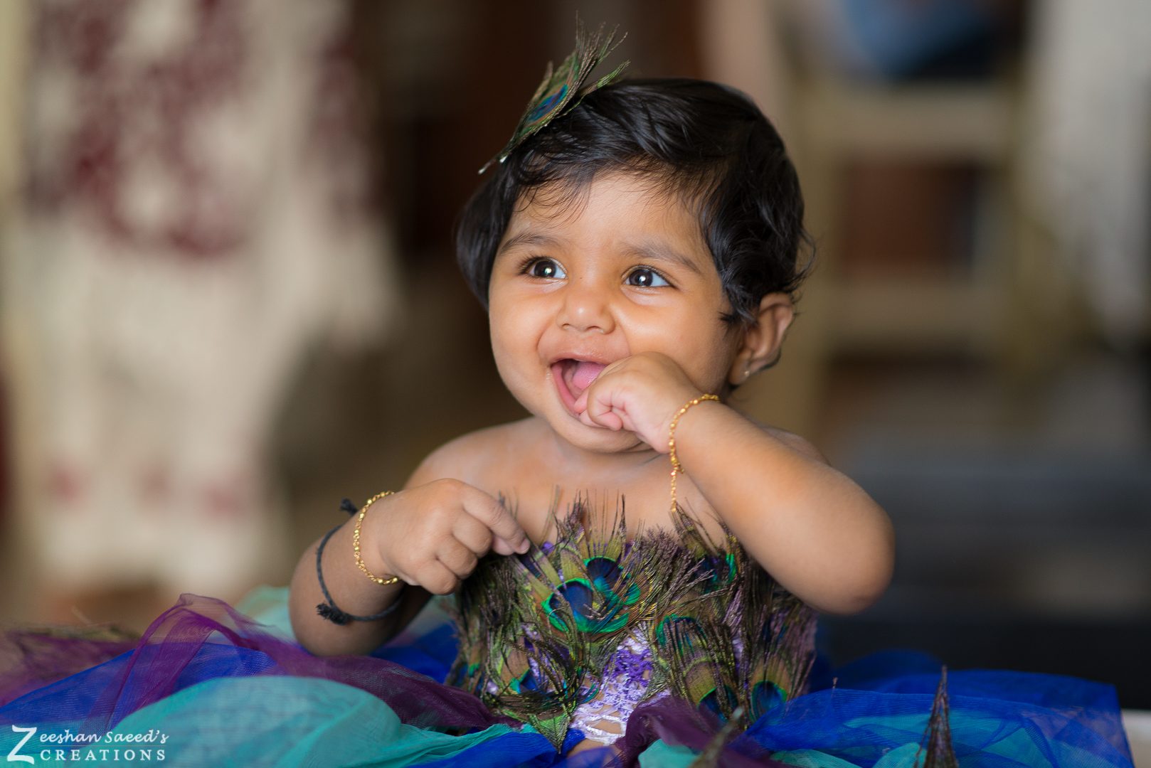 My baby daughter laughing in a peacock-feather dress