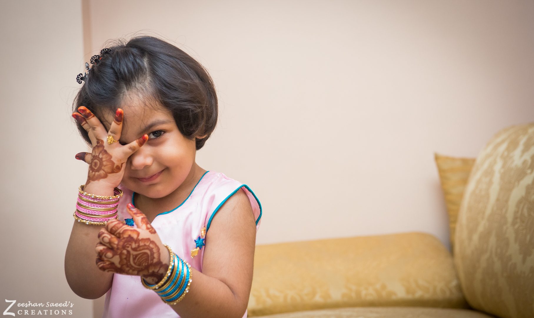 My niece with henna-patterned hands, peeking through her fingers